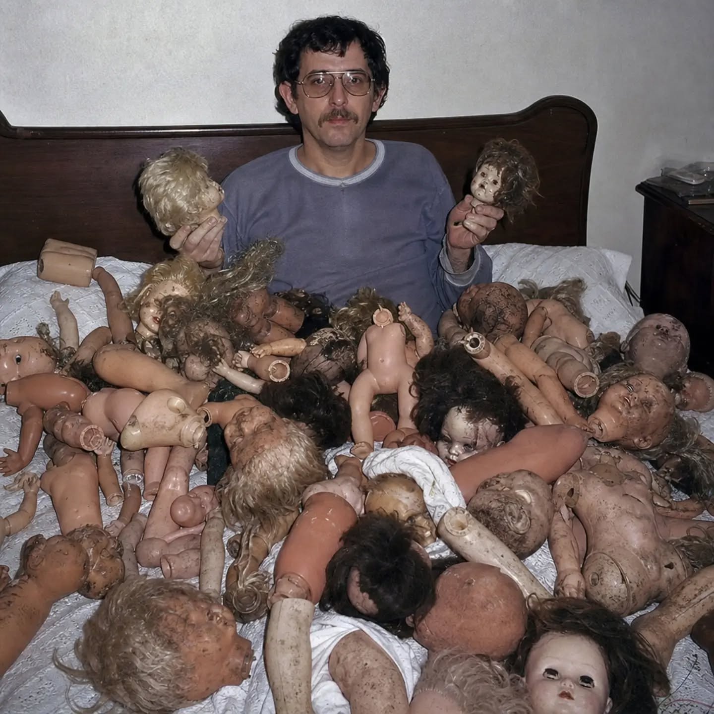 AI slop artwork of a collector seated among many broken dolls on a bed